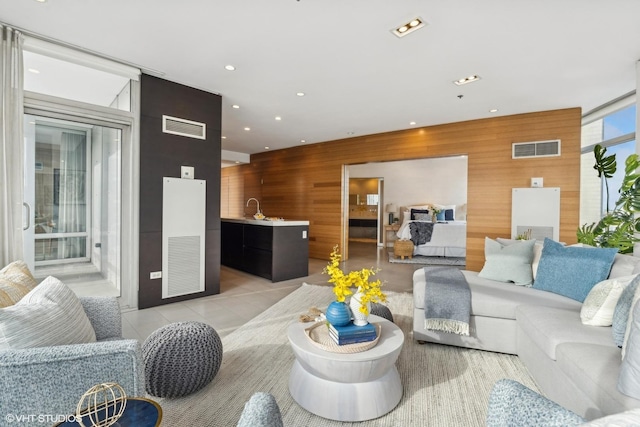 living room featuring light tile patterned floors and wood walls