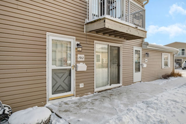 snow covered property entrance featuring a balcony