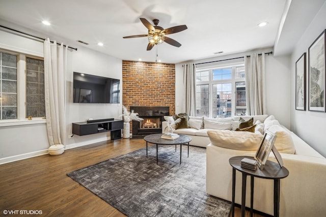 living room featuring dark wood-type flooring, ceiling fan, and a fireplace