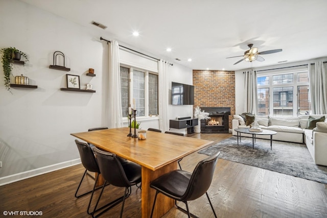 dining space featuring a fireplace, dark hardwood / wood-style floors, and ceiling fan