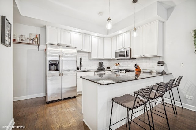 kitchen featuring white cabinetry, stainless steel appliances, kitchen peninsula, and hanging light fixtures