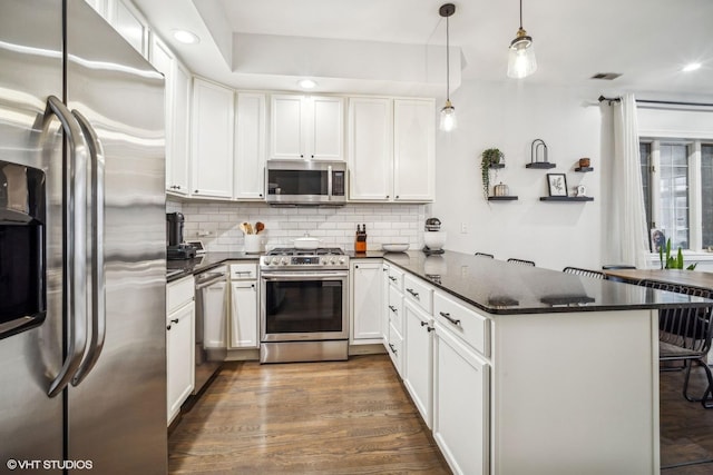 kitchen with pendant lighting, kitchen peninsula, white cabinets, and appliances with stainless steel finishes