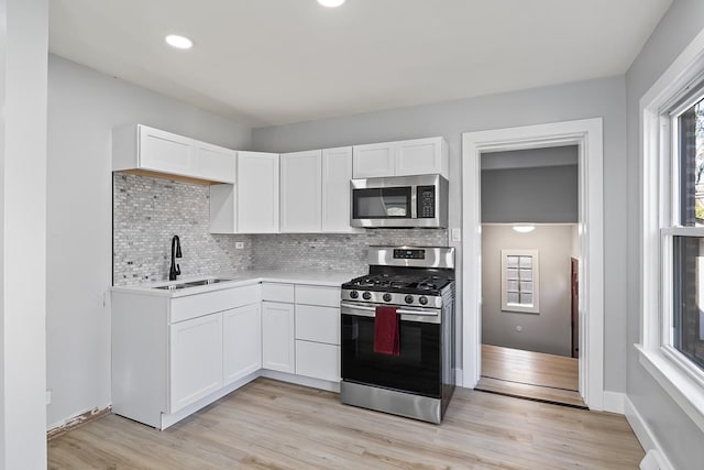 kitchen with white cabinetry, stainless steel appliances, sink, and tasteful backsplash