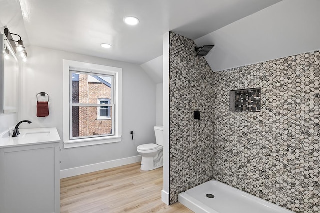 bathroom featuring vanity, tiled shower, hardwood / wood-style floors, and toilet