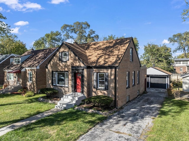 english style home featuring a garage, an outbuilding, and a front lawn