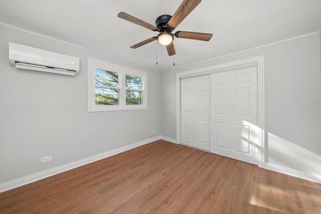 unfurnished bedroom featuring wood-type flooring, ornamental molding, a wall mounted air conditioner, and a closet