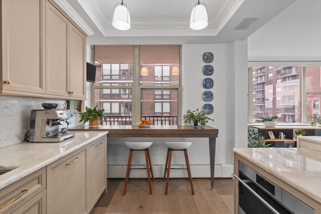 kitchen with pendant lighting, a baseboard radiator, ornamental molding, and a tray ceiling