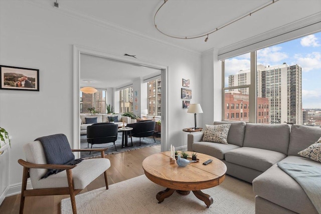 living room with crown molding, a healthy amount of sunlight, and hardwood / wood-style floors