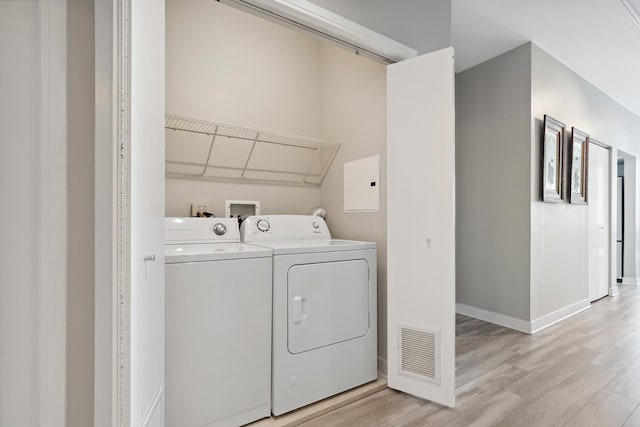 clothes washing area featuring light hardwood / wood-style floors and washer and dryer