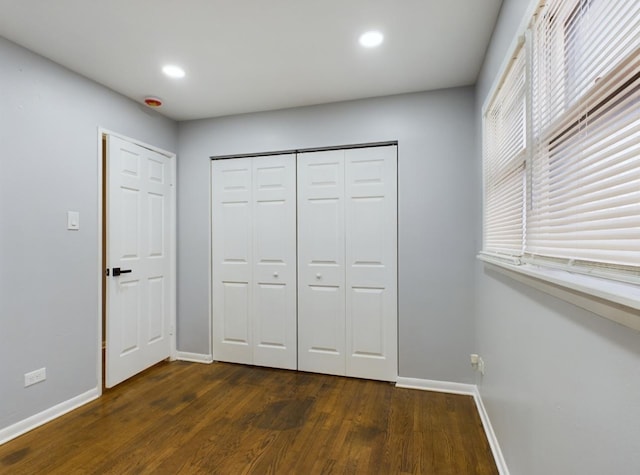 unfurnished bedroom with dark hardwood / wood-style flooring and a closet