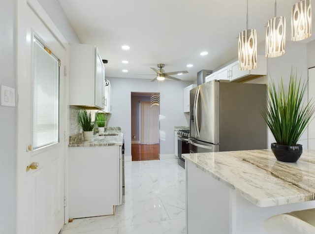 kitchen with a breakfast bar, ceiling fan, white cabinetry, stainless steel appliances, and decorative light fixtures