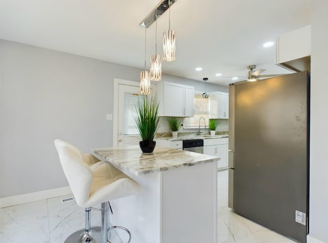 kitchen with ceiling fan, white cabinetry, stainless steel appliances, a kitchen breakfast bar, and a kitchen island