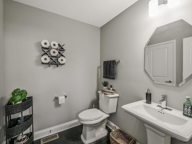 bathroom featuring toilet, sink, and heating unit