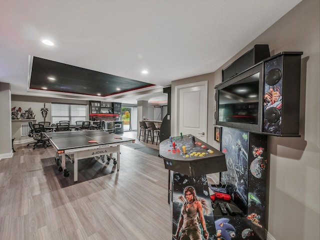 rec room with a raised ceiling and light wood-type flooring