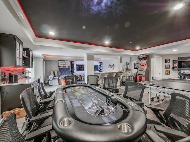 game room with crown molding, bar area, a tray ceiling, and hardwood / wood-style floors