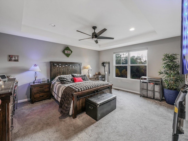 carpeted bedroom featuring ceiling fan and a tray ceiling