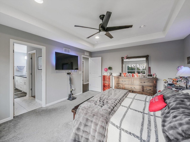 carpeted bedroom with connected bathroom, a tray ceiling, and ceiling fan