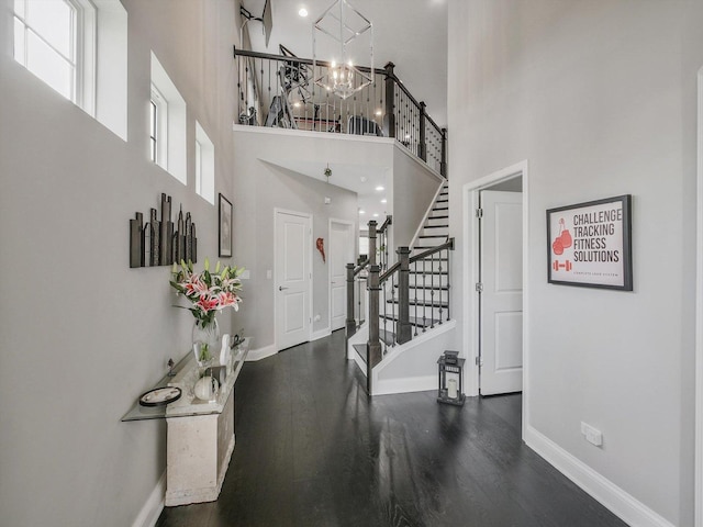 foyer featuring a towering ceiling, dark hardwood / wood-style floors, and a notable chandelier