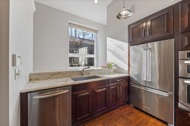 kitchen featuring pendant lighting, sink, stainless steel appliances, dark hardwood / wood-style floors, and light stone counters