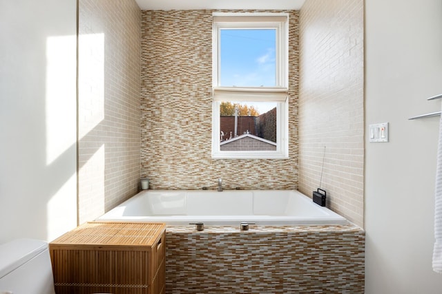 bathroom with a relaxing tiled tub and toilet