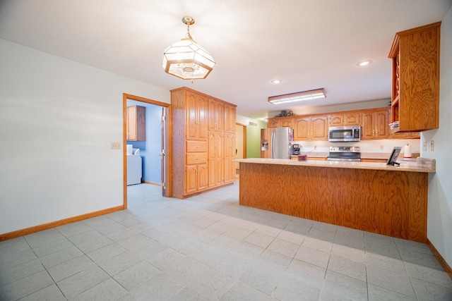 kitchen with stainless steel appliances, washer / dryer, hanging light fixtures, and kitchen peninsula