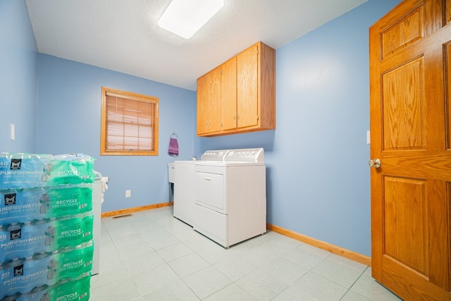 clothes washing area with cabinets, washing machine and clothes dryer, and a textured ceiling