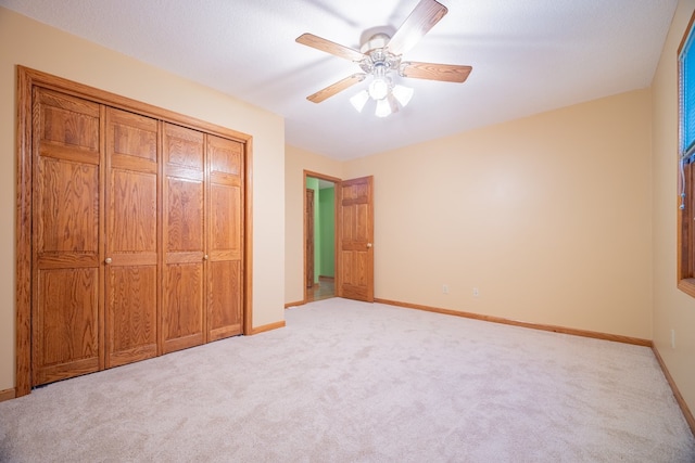 unfurnished bedroom with light carpet, ceiling fan, and a closet