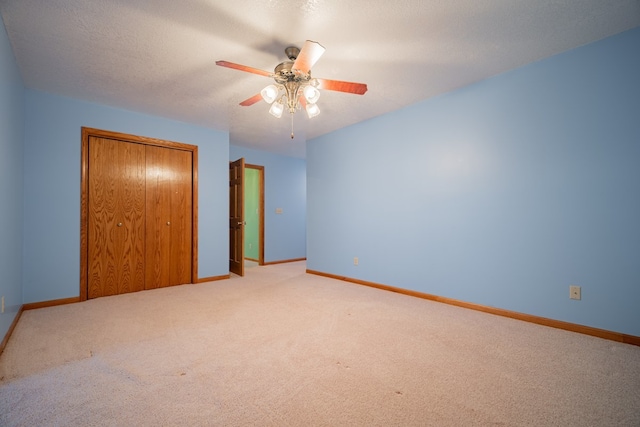 unfurnished bedroom with ceiling fan, carpet floors, a textured ceiling, and a closet