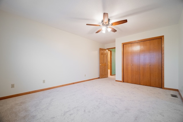 unfurnished bedroom with light carpet, a closet, and ceiling fan