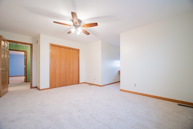 unfurnished bedroom with ceiling fan, a closet, and light carpet