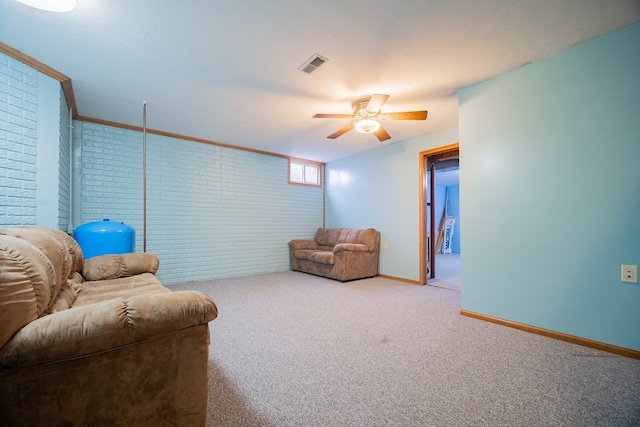 living area with ceiling fan, brick wall, carpet floors, and ornamental molding