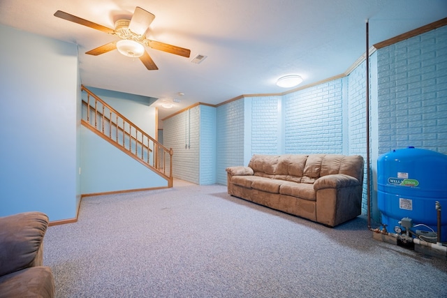 living room featuring ornamental molding, brick wall, carpet flooring, and ceiling fan