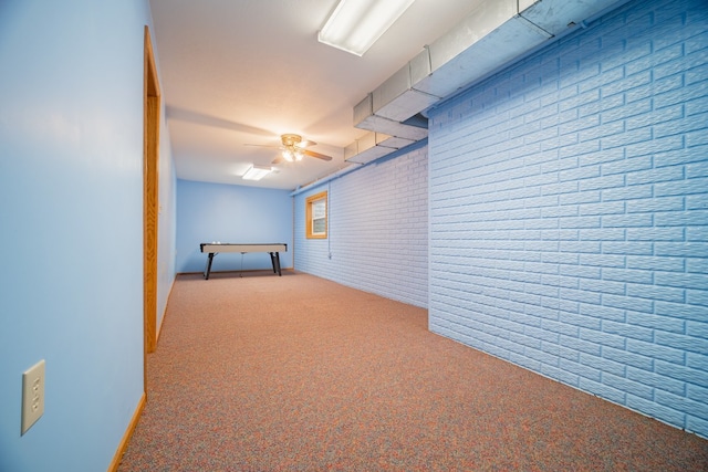 basement with ceiling fan, brick wall, and light carpet