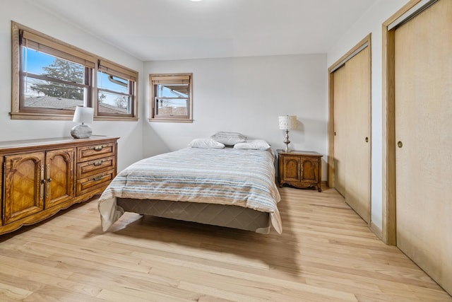 bedroom featuring two closets and light wood-type flooring