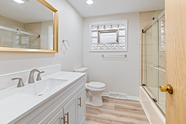 full bathroom featuring enclosed tub / shower combo, vanity, toilet, and wood-type flooring