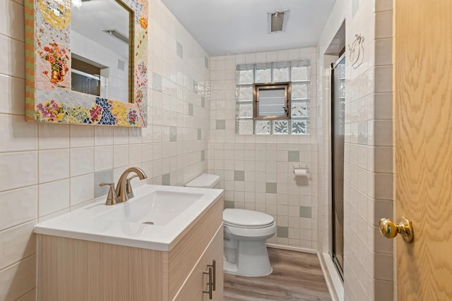 bathroom featuring hardwood / wood-style floors, tile walls, vanity, walk in shower, and toilet