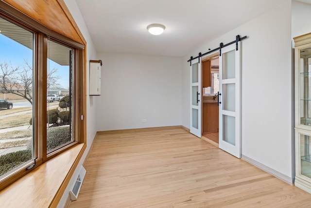 corridor with a barn door and light hardwood / wood-style flooring