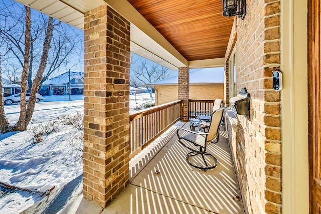 snow covered back of property with a porch