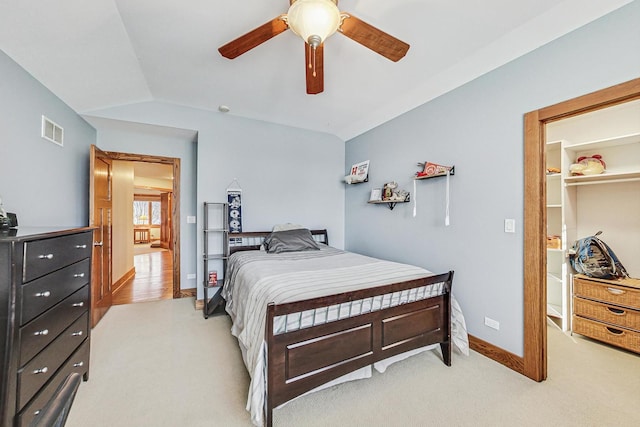 carpeted bedroom with lofted ceiling, a walk in closet, and ceiling fan