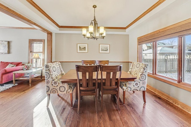 dining area with a notable chandelier, crown molding, dark hardwood / wood-style floors, and a raised ceiling