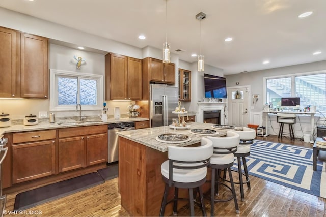 kitchen featuring a breakfast bar, sink, hardwood / wood-style flooring, hanging light fixtures, and stainless steel appliances