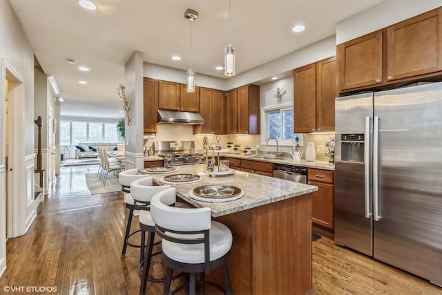 kitchen with a kitchen island, pendant lighting, sink, a kitchen breakfast bar, and stainless steel appliances