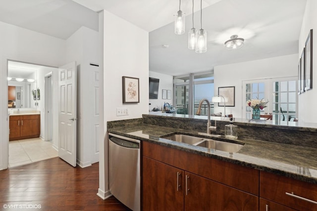 kitchen with sink, dark wood-type flooring, dishwasher, decorative light fixtures, and dark stone counters