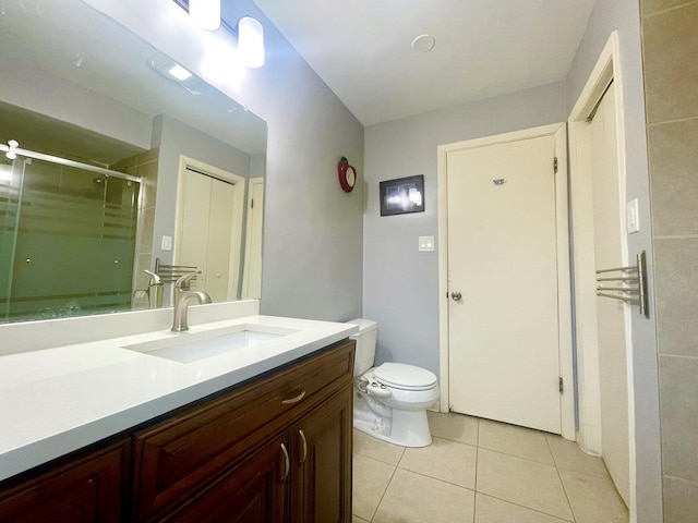 bathroom featuring tile patterned flooring, vanity, a shower with shower door, and toilet