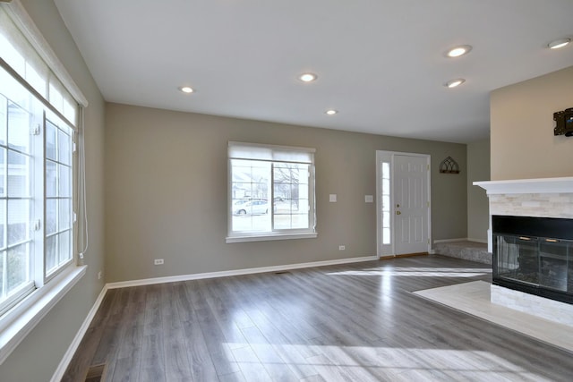 unfurnished living room with a multi sided fireplace, dark hardwood / wood-style floors, and a wealth of natural light