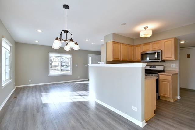 kitchen with appliances with stainless steel finishes, plenty of natural light, hanging light fixtures, and light brown cabinets