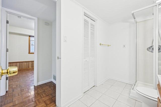 bathroom with parquet flooring, toilet, and a shower with door