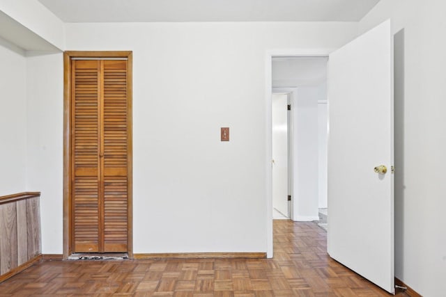 unfurnished bedroom featuring parquet floors and a closet