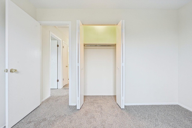 unfurnished bedroom featuring light colored carpet and a closet