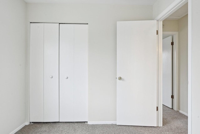 unfurnished bedroom featuring light carpet and a closet